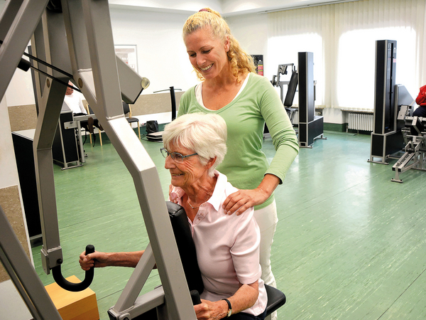 Physiotherapeutin leitet Seniorin beim Krafttraining an Physiotherapeutin leitet Seniorin beim Krafttraining an